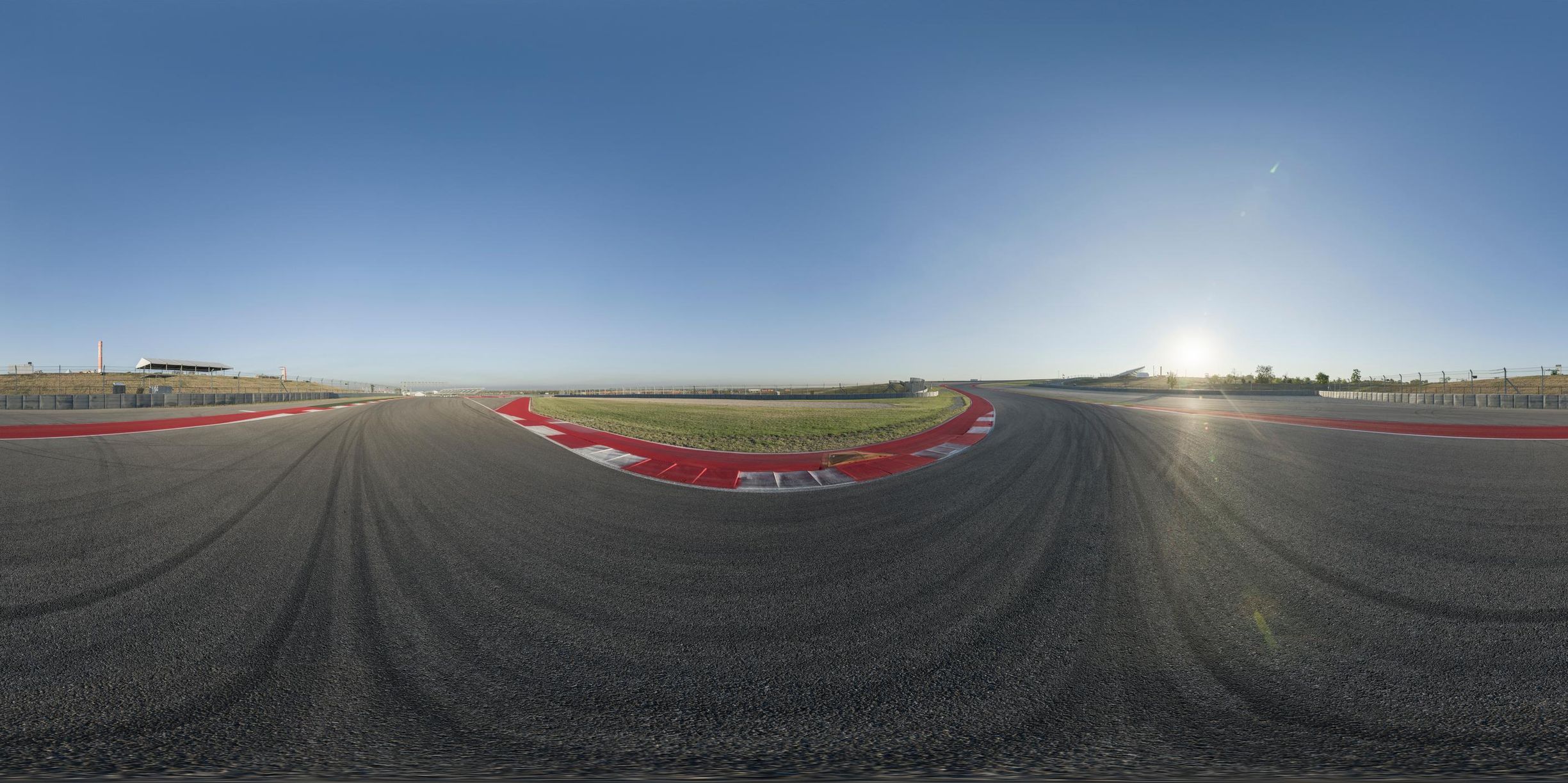a view of a car racing around the track with sun in background while seen through the lens