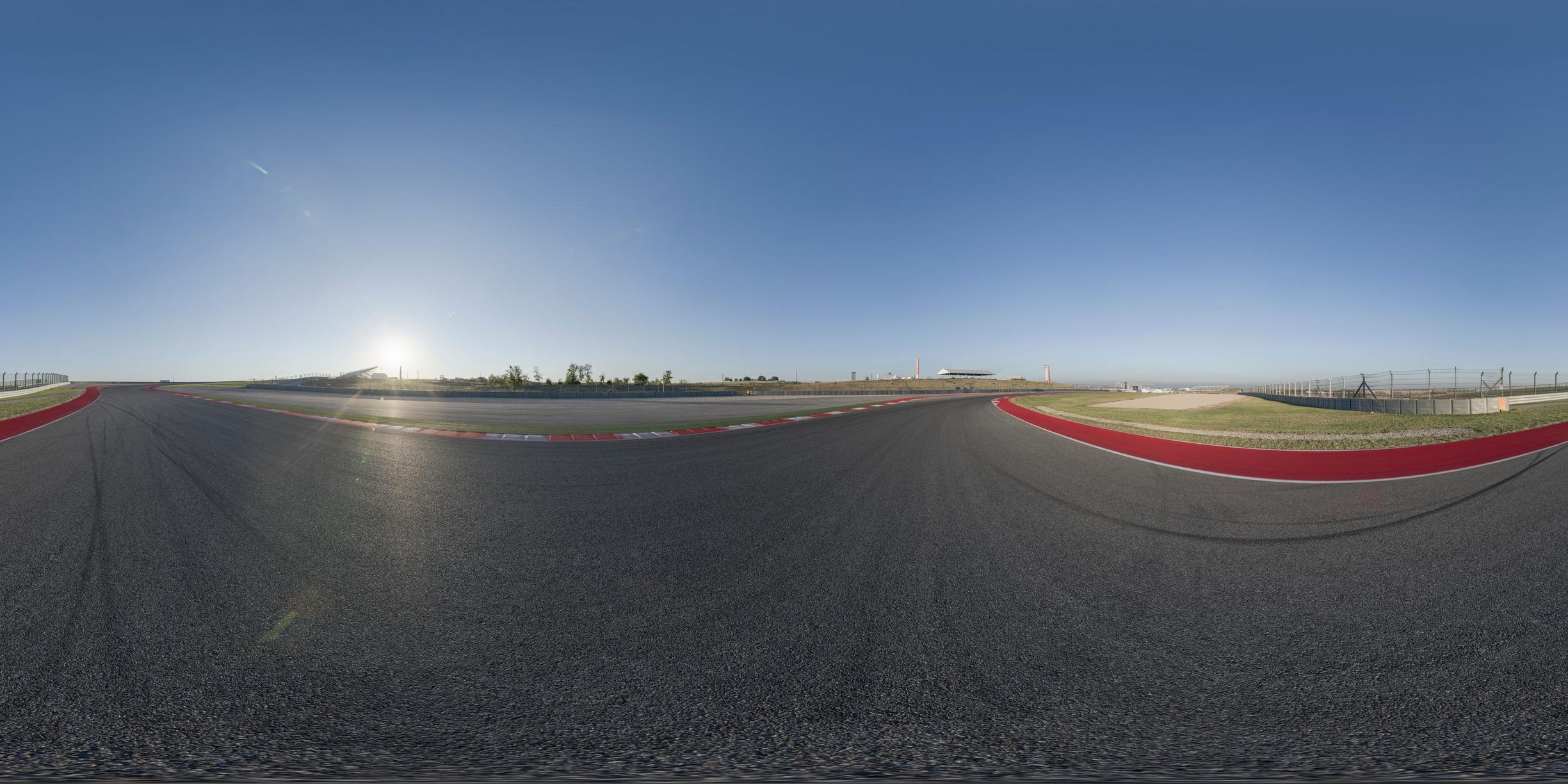 the sun is setting on a track with an asphalt course in front of it and red and green markings