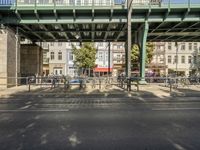 some benches are in front of a bridge in the city of brussels, france in this view a few cars pass by