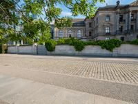 the skateboarder is in the middle of the pavement, looking out at a building