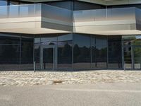 an outside building with a brick sidewalk and glass doors on one side and on the other side,