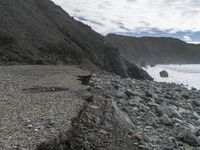 this is a stone path going down a rocky beach next to a cliff line on the water