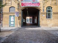 a brick building with a red and white sign on the front doorway of it, saying kammbaaa lamp