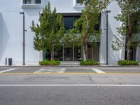 a building with trees next to a street and curbs on a clear day at a crosswalk