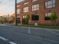 an empty street in front of a large red brick building on the other side of the road is a street light that has a line for motorists