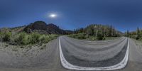 a panoramic view of the long straight road on a sunny day with the sun over a mountain