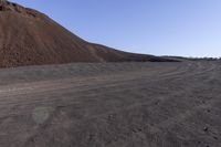 a large mound of dirt sitting in the middle of a desert area with a clear blue sky