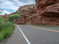 this is an image of a road with yellow and white lines leading up to a rock formation