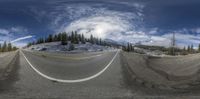 a fisheye lens view of mountains and sky from a highway intersection at high altitude