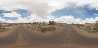 an empty road with some dirt and bushes on each side in the middle of it