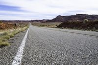 a long road goes into the desert with rocks and grass on both sides of it