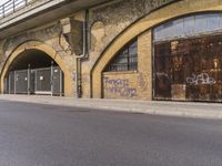 a closed down building is seen on a street side walk outside of some buildings, with graffiti all over it