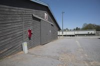 a parking lot with a building and trashcan behind it and the door and roof is missing