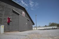 a parking lot with a building and trashcan behind it and the door and roof is missing