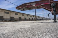 a stop sign sits in a empty area in front of an abandoned building and an old parking lot