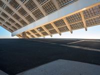 an empty parking lot with an elevated roof and a sidewalk underneath it that's black