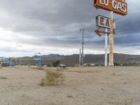 an abandoned sign for an old - fashioned gas station sits in the sand at dusk