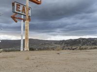 an abandoned sign for an old - fashioned gas station sits in the sand at dusk