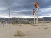 an abandoned sign for an old - fashioned gas station sits in the sand at dusk