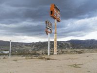 an abandoned sign for an old - fashioned gas station sits in the sand at dusk