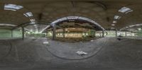 a fisheye view of the inside of an abandoned building with cement floors and ceiling