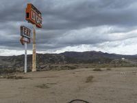 an abandoned intersection in the middle of a deserted desert area on a cloudy day with mountains in the distance