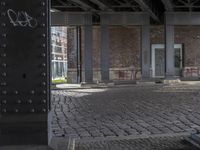 graffiti adorns the pillars in the abandoned space outside of a building with brickwork and walls