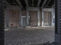 graffiti adorns the pillars in the abandoned space outside of a building with brickwork and walls