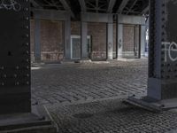 graffiti adorns the pillars in the abandoned space outside of a building with brickwork and walls