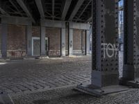 graffiti adorns the pillars in the abandoned space outside of a building with brickwork and walls