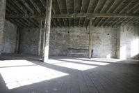 empty brick warehouse space with open floor plan and windows, in the early evening sun