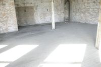 empty brick warehouse space with open floor plan and windows, in the early evening sun