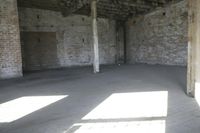 empty brick warehouse space with open floor plan and windows, in the early evening sun