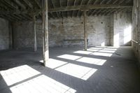 empty brick warehouse space with open floor plan and windows, in the early evening sun