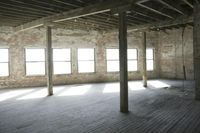 empty brick warehouse space with open floor plan and windows, in the early evening sun