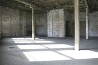 empty brick warehouse space with open floor plan and windows, in the early evening sun