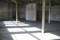 empty brick warehouse space with open floor plan and windows, in the early evening sun