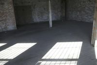 empty brick warehouse space with open floor plan and windows, in the early evening sun