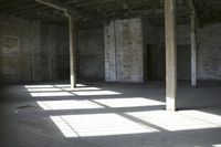 empty brick warehouse space with open floor plan and windows, in the early evening sun