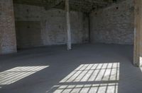 empty brick warehouse space with open floor plan and windows, in the early evening sun