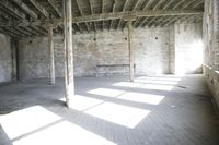 empty brick warehouse space with open floor plan and windows, in the early evening sun
