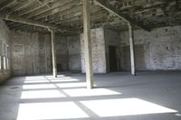 empty brick warehouse space with open floor plan and windows, in the early evening sun
