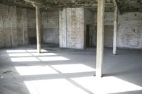 empty brick warehouse space with open floor plan and windows, in the early evening sun