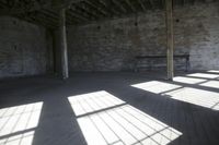 empty brick warehouse space with open floor plan and windows, in the early evening sun
