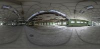 an empty warehouse, full of concrete and with circular mirrors, at the end of it