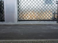 there is a woman standing outside a glass building that looks like an abstract structure with a geometric pattern