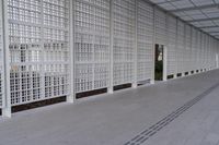 a long white wall covered with a latticed area of bricks and glass blocks on the ground