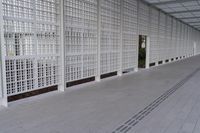 a long white wall covered with a latticed area of bricks and glass blocks on the ground