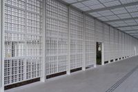 a long white wall covered with a latticed area of bricks and glass blocks on the ground