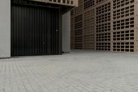 the small building has shuttered doors open on one side and some black bars along one side